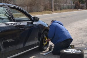Marcus Argyros changes his tire on the side of the road after hitting a pothole. Photo by Barbara Donlon