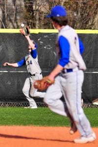 Comsewogue’s Ryan Szalay makes a grab at the warning track in the Warriors 9-4 comeback win over Sayville Thursday. Photo by Bill Landon