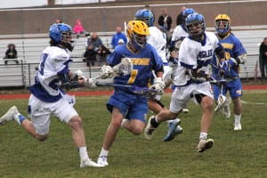 Comsewogue's Trevor Kennedy squeezes between two Hauppauge players in a match on April 7. Photo by Desirée Keegan