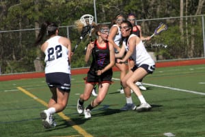 Middle Country’s Amanda Masullo squeezes between Smithtown West’s Kalya Kosubinsky and Katie Aldrich as she moves the ball up the field in the Mad Dogs’ 17-13 win over the Bulls on May 8. With the win, Middle Country goes undefeated in regular season play. Photo by Desirée Keegan