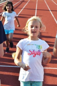 A little girl crosses the finish line in a 55-meter run. Photo by Alex Petroski