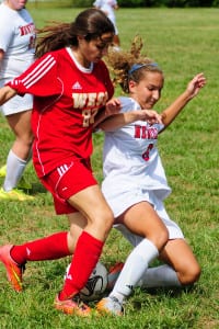 Newfield's Sierra Rosario battles a Half Hollow Hills West opponent for possession. Photo by Bill Landon