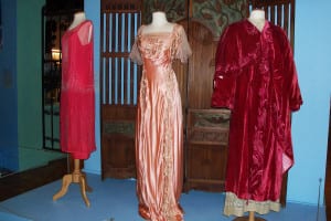 From left, 1920s pink party dress with silk faux glass beading, gift of Timothy Smith; embroidered silk gown, 1908, gift of Mrs. B. Langdon and Mrs. William Floyd Nichols; embroidered silk velvet evening opera cape, 1912, gift of Grace Rumbough. Photo by Ellen Barcel