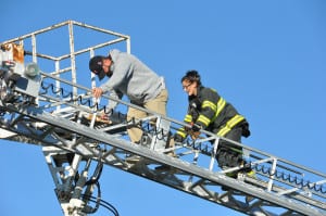 Dix Hills firefighter Jacquelyn Stio helps coach Tim Kopiske to safety after the Smithtown High School East football coach got stuck in a malfunctioning bucket truck at a homecoming game. Photo by Steve Silverman