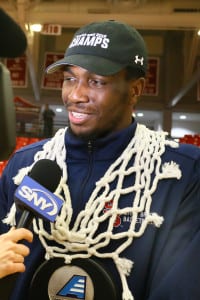 Stony Brook University men's basketball standout Jameel Warney speaks to reporters with the net draped around his neck after his team earned an automatic bid to the NCAA Tournament. Photo by John Griffin/Stony Brook University