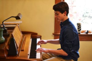 Julien Rentsch practices the piano at his home in Huntington. Photo by Alex Petroski