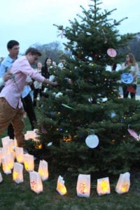 Residents wrote a message or the name of someone they lost to a drug overdose at the top of the white bags and placed them around the base of Gabriel Phillippe’s Belonging Tree, above, during the candlelight ceremony. Photo by Giselle Barkley 