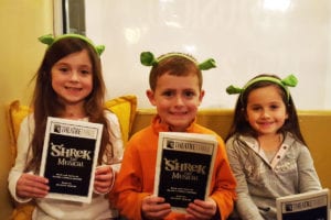 From left, Aida, Liam and Maddox pose with the program and their green ogre ears after the Shrek show last Saturday night. Photo by Michael Tessler