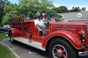 The longest serving member of the Stony Brook Fire Department, Peter Gustafson, sits in the department’s antique truck dating from 1939. Photo by Donna Newman