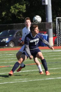 Huntington's Matt Gelb heads the ball over a Smithtown West player and into the Bulls' zone. Photo by Desirée Kegan